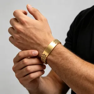 Close-up of gold-tone men's steel ID bracelet featuring a watch-style jubilee link band