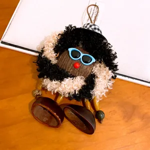 Vue rapprochée d'un pendentif de sac artisanal en bois et peluche avec lunettes de soleil
