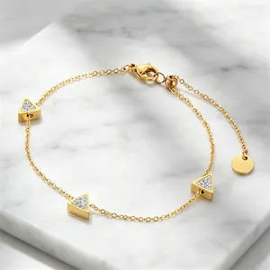 Detailansicht des eleganten goldenen Armbands mit geometrischen Dreiecken auf Marmor.
