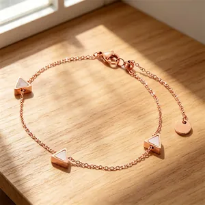 Nahaufnahme eines roségoldenen Armbands mit dreieckigen Perlmutt-Inlays auf Holz