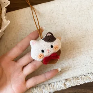 Gros plan exquis d'un pendentif en peluche chat fait main avec noeud rouge et cordon