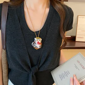 Vue détaillée d'un collier avec pendentif chat en tissu fait main, chapeau jaune et nœud