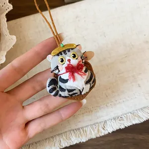Gros plan d'un mignon pendentif de poupée chat brodé à la main avec un nœud rouge
