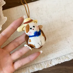 Gros plan d'un collier pendentif chat en tissu fait main avec chapeau de paille et nœud