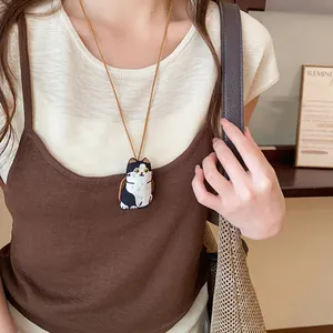 Vue détaillée d'un joli collier pendentif chat en tissu brodé porté par un modèle.