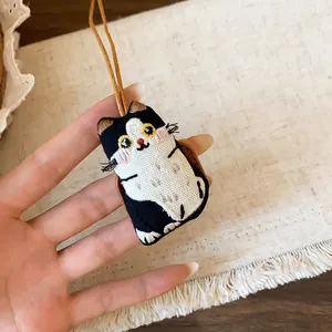 Vue détaillée d'un adorable pendentif chat brodé à la main sur un fond en tissu doux