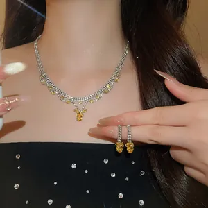 Detailopname van sprankelende gele zirkoon ketting en oorbellen set op model.