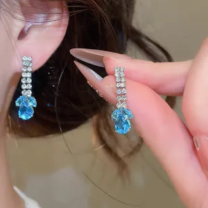Detail van elegante zilveren oorbellen met blauwe waterdruppelhangers en zirkonia's