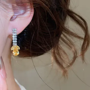 Gedetailleerd overzicht van luxe sprankelende gele zirkonia druppeloorbellen op model