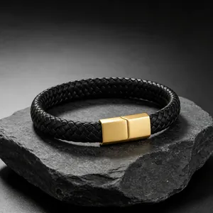 Detailopname van een gevlochten zwarte leren herenarmband met gouden magneetsluiting