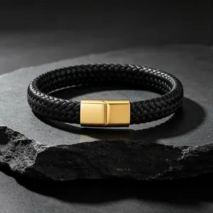 Gedetailleerde weergave van zwarte gevlochten leren herenarmband met gouden magnetische sluiting