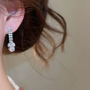 Close-up van fonkelende zirkonia oorbellen met waterdruppel hanger aan het oor