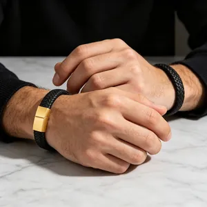 Detail van een zwarte gevlochten leren herenarmband met een gouden magnetische sluiting