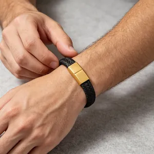 Detailopname van een gevlochten leren herenarmband met een matte gouden magneetsluiting.