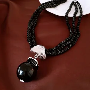 Élégant collier multi-rangs de perles noires avec un grand pendentif sphérique brillant
