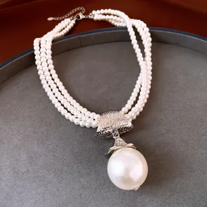 Gros plan d'un collier de perles multi-rangs de style français avec un grand pendentif perle.