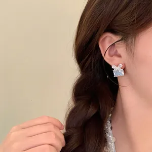 Gros plan de boucles d'oreilles nœud en zircon carré portées par un mannequin asiatique