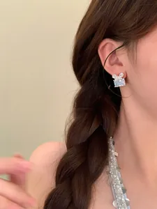 Gros plan détaillé sur d'élégantes boucles d'oreilles nœud en zircon carré pour femme