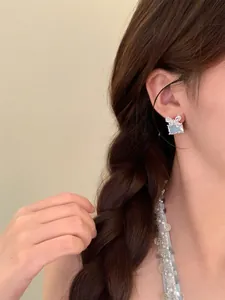 Gros plan de boucles d'oreilles nœud papillon en zircon géométrique sur l'oreille du mannequin