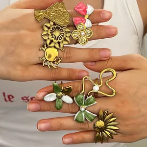 Close-up of vintage enamel rings with floral, bow, and crab designs on fingers