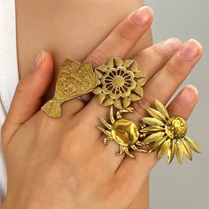 Close-up view of vintage gold-plated stainless steel flower and crab rings on a hand