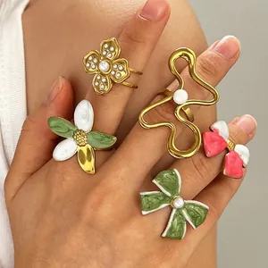 Detailed close-up shot of vintage colorful enamel flower and bow rings worn on a hand