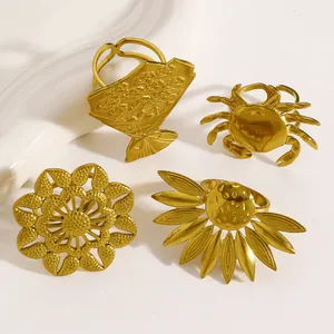 Macro view of four gold-toned stainless steel rings with flower and crab designs.