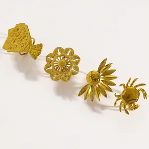 Detail shot of four vintage gold stainless steel rings with flower and crab motifs.