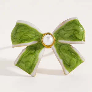 Close-up detail of a vintage green enamel bow ring with a delicate pearl centerpiece.