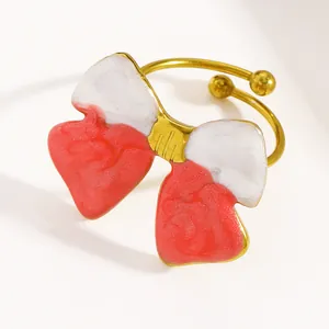 Detailed macro view of vintage stainless steel open ring featuring a red and white enamel bow