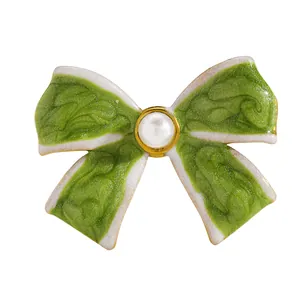 Macro detail of a vintage-style green enamel bow charm with a central pearl for a ring