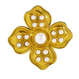 Detail of a gold-plated flower ring featuring a central faux pearl and enamel finish.