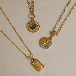 Detailansicht goldener Edelstahlketten mit Sonnen- und Mondanhängern und Strasssteinen