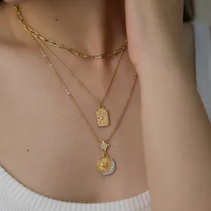 Detailaufnahme einer mehrlagigen goldenen Halskette mit Sonnen- und Mondanhängern