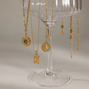 Detailansicht von vergoldeten Halsketten mit Sonnen- und Mondanhängern an einem Glas