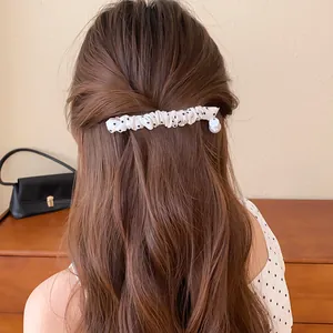 Elegante close-up van een witte geplooide haarclip met polkadots op golvend bruin haar