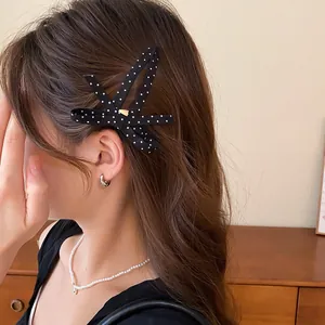 Detailopname van een zwart-witte gestippelde stoffen haarklem op het haar van een model
