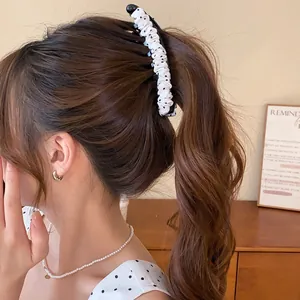 Elegante haarklem in Koreaanse stijl met polkadots en ruches op de paardenstaart van een model.