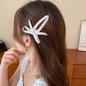 Gedetailleerde weergave van een zwart-witte polkadothaarclip van stof bij een vrouw