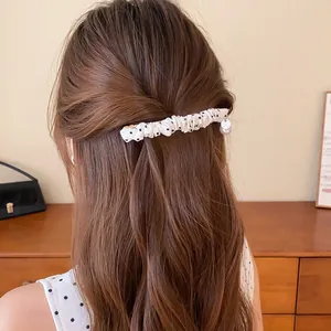 Detail van een haarklem met stippen in Koreaanse stijl op lang golvend bruin haar