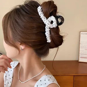 Detail van een elegante witte haarspeld met stippenstof die op een knot wordt gedragen