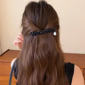 Gedetailleerd achteraanzicht van een vrouw met een geplooide zwart-witte stoffen haarklem