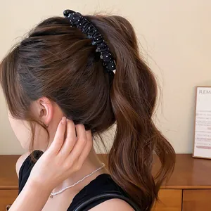 Detailweergave van een zwart-witte gestippelde haarclip van geplooide stof in het haar
