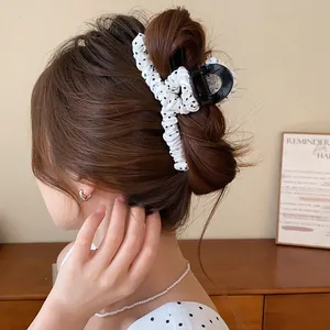 Close-up van een elegante geplooide zwart-witte polkadot haarklem gebruikt in een knotje