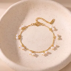 Close-up view of gold stainless steel bracelet with dainty white pearls in a ceramic bowl