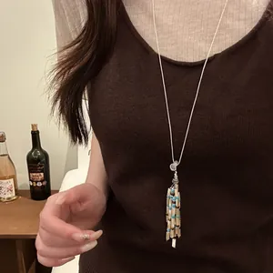 Detail view of a vintage bohemian beaded tassel necklace on a brown knit sweater
