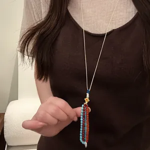 Detailed view of a bohemian beaded tassel necklace with pearl and gold accents on a model