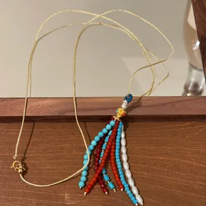 Detail view of Bohemian beaded tassel necklace with turquoise, pearls and red beads