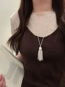 Detailed view of a long Bohemian pearl tassel necklace worn elegantly over a brown tank top
