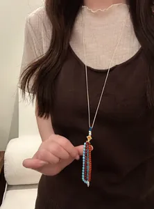 Close-up detail of bohemian beaded tassel necklace on a model wearing a brown top.